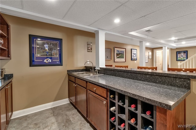 bar featuring baseboards, a sink, wet bar, a raised ceiling, and stairway