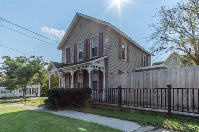 view of front of home featuring covered porch, fence, and a front yard