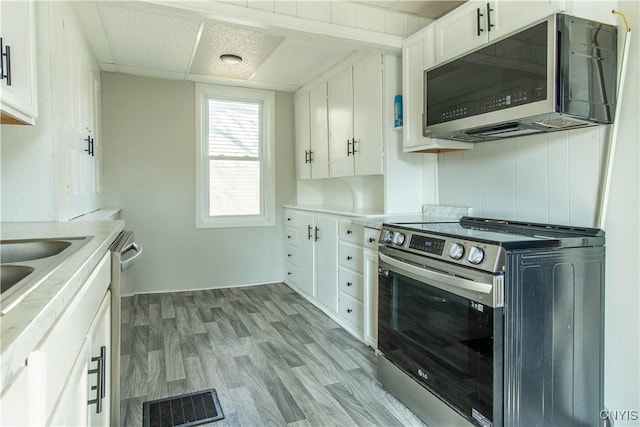 kitchen with light wood-type flooring, visible vents, white cabinetry, light countertops, and appliances with stainless steel finishes