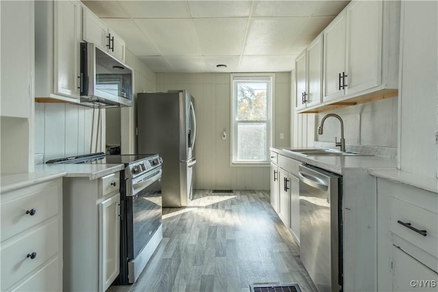kitchen featuring a sink, light wood-style floors, white cabinets, light countertops, and appliances with stainless steel finishes