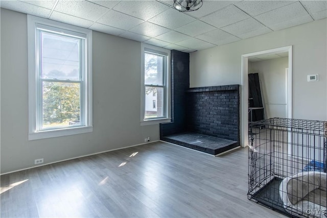 unfurnished living room with baseboards, a drop ceiling, and wood finished floors