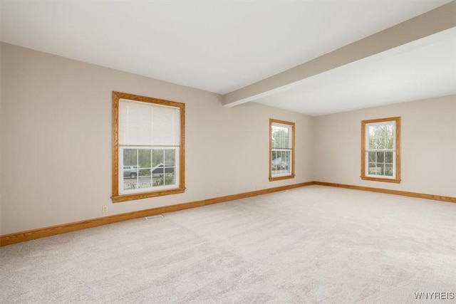 unfurnished room with baseboards, beamed ceiling, and light colored carpet