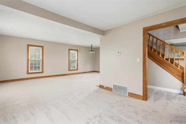 unfurnished room featuring a notable chandelier, carpet, baseboards, and visible vents