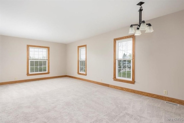 spare room with baseboards, a wealth of natural light, and light carpet