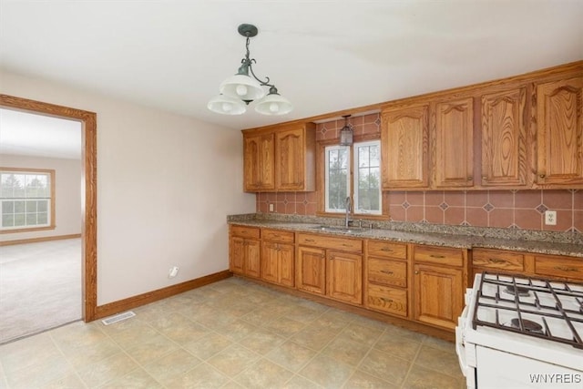kitchen with baseboards, brown cabinets, a healthy amount of sunlight, and a sink