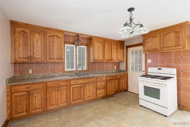 kitchen with a sink, tasteful backsplash, brown cabinets, white gas range, and a notable chandelier