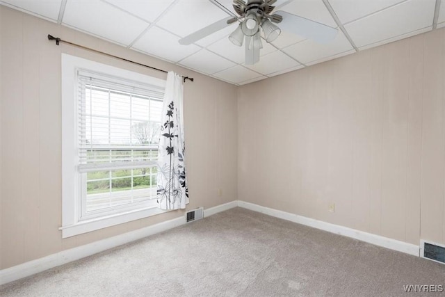 empty room with carpet flooring, visible vents, baseboards, and a ceiling fan