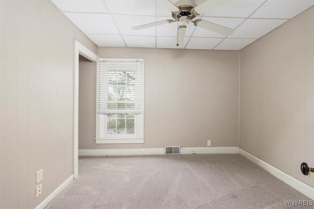 unfurnished room featuring carpet, visible vents, ceiling fan, a paneled ceiling, and baseboards