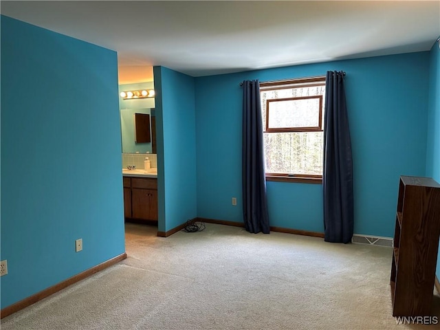 unfurnished bedroom with light colored carpet, connected bathroom, and baseboards