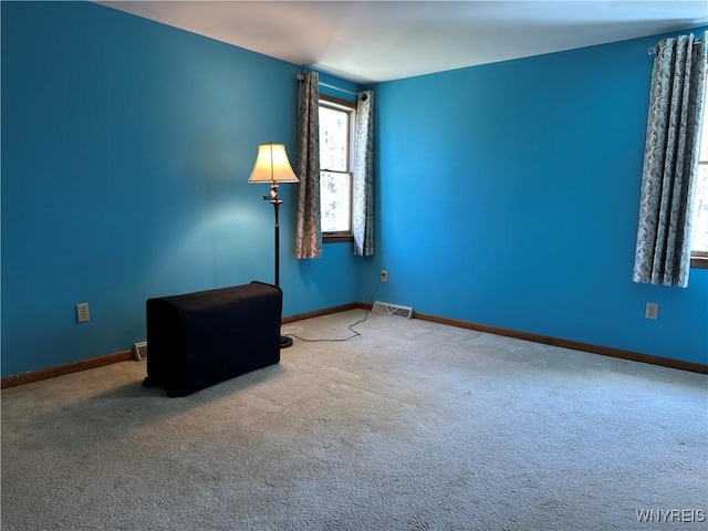 empty room featuring carpet floors, baseboards, and visible vents