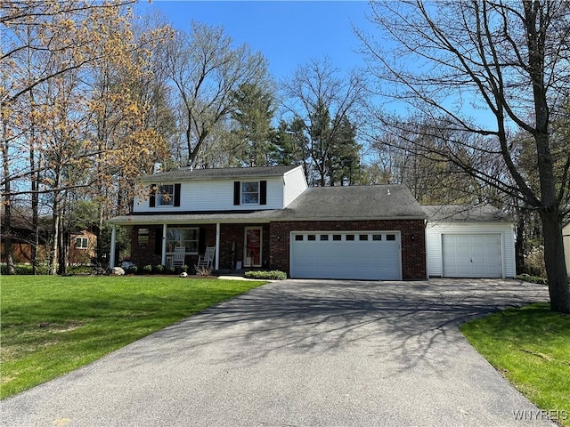 traditional-style house with an attached garage, a front lawn, a porch, brick siding, and driveway