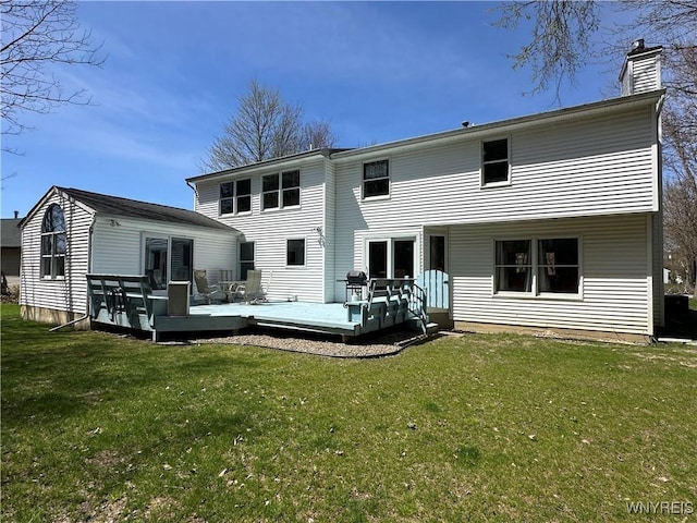 rear view of house with a yard, a wooden deck, and a chimney