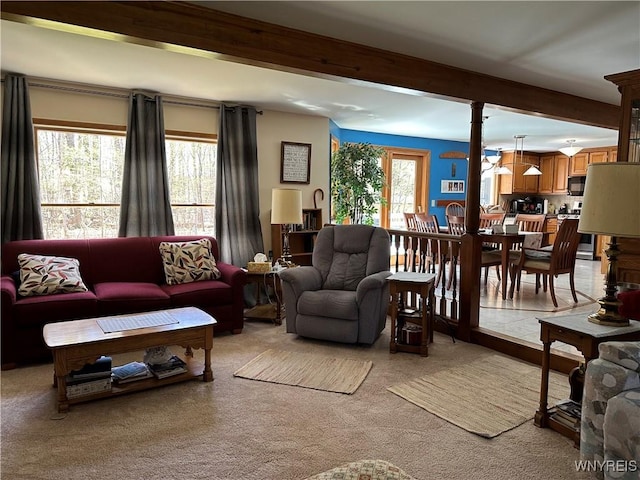 living area with light colored carpet and beamed ceiling