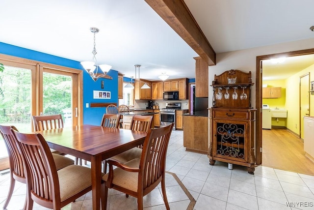 103 Old Orchard Ln, Orchard Park, NY 14127 - dining space with washer / clothes dryer, light tile patterned floors, and a chandelier