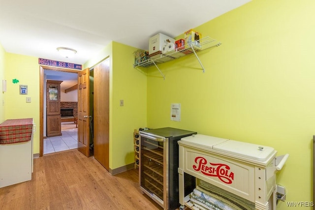 103 Old Orchard Ln, Orchard Park, NY 14127 - laundry room with light wood finished floors, washer and clothes dryer, a large fireplace, wine cooler, and baseboards