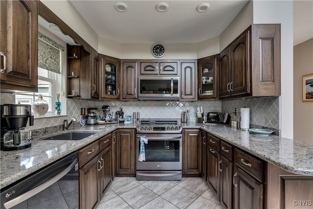 44458 County Route 100, Alexandria, NY 13640 - kitchen featuring a sink, stainless steel appliances, dark brown cabinetry, decorative backsplash, and light stone counters