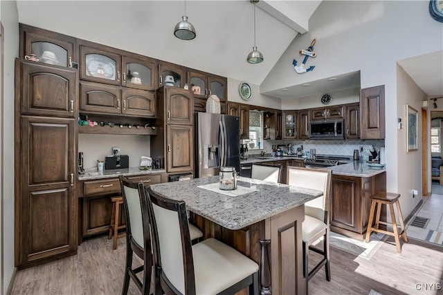 44458 County Route 100, Alexandria, NY 13640 - kitchen with glass insert cabinets, a center island, dark brown cabinetry, a kitchen breakfast bar, and stainless steel appliances