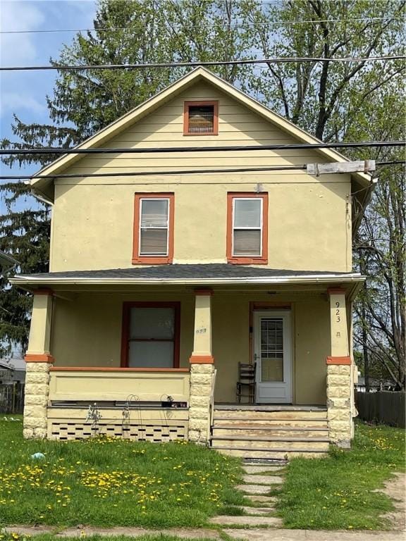 american foursquare style home featuring a porch, stucco siding, and a front yard
