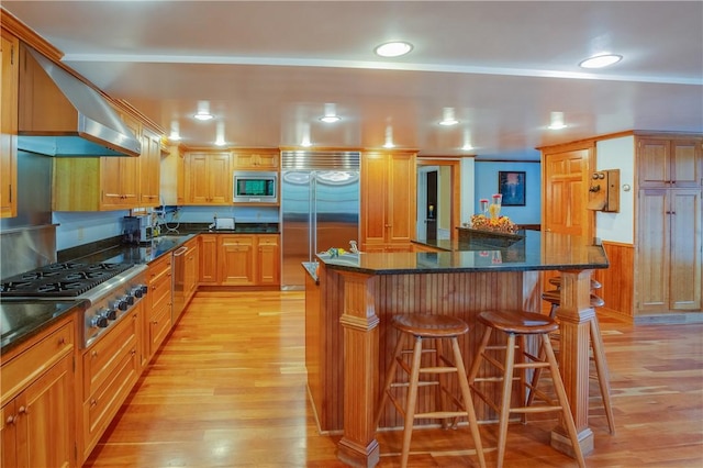 kitchen with built in appliances, light wood-style floors, a kitchen breakfast bar, and a center island