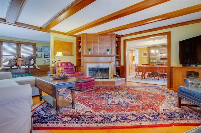 living room featuring a fireplace, wainscoting, wood finished floors, and beam ceiling
