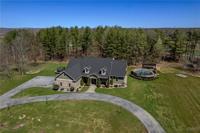 view of front of house featuring a front yard, a forest view, and curved driveway