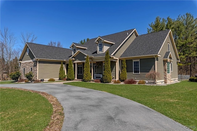 craftsman-style house featuring aphalt driveway, roof with shingles, and a front yard