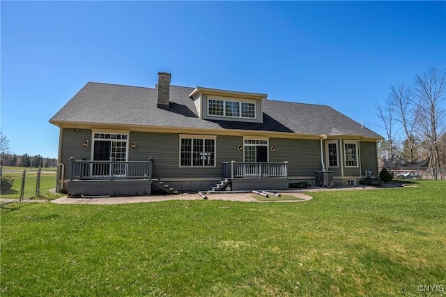 back of property with a deck, fence, stairway, a chimney, and a lawn