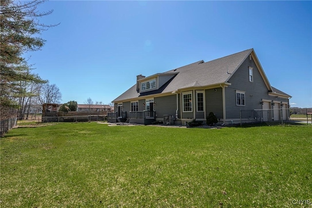 rear view of property with a fenced backyard, a chimney, and a yard