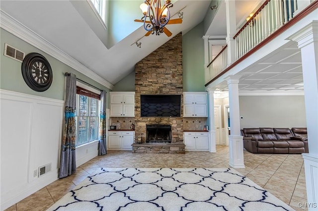 unfurnished living room with a fireplace, visible vents, decorative columns, and high vaulted ceiling