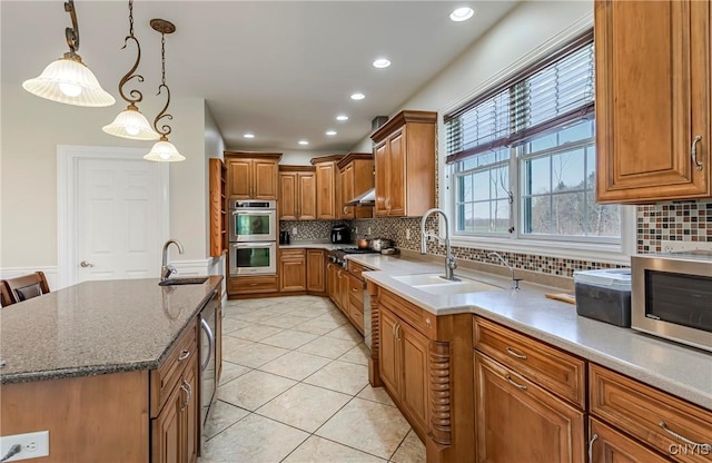 kitchen with a sink, brown cabinets, decorative backsplash, light tile patterned floors, and appliances with stainless steel finishes