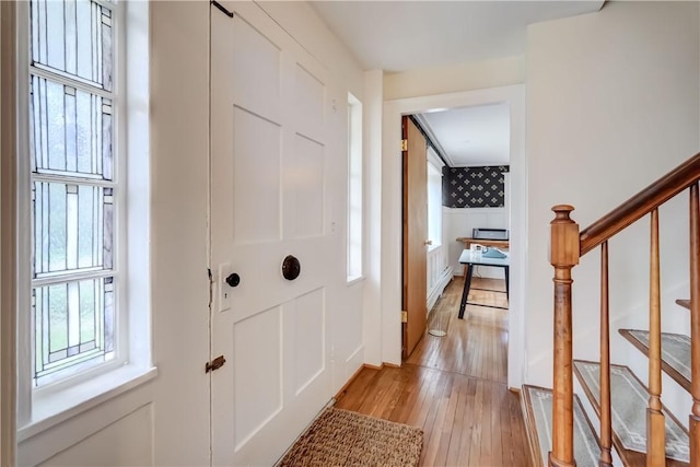 corridor featuring stairway, light wood-type flooring, and wallpapered walls