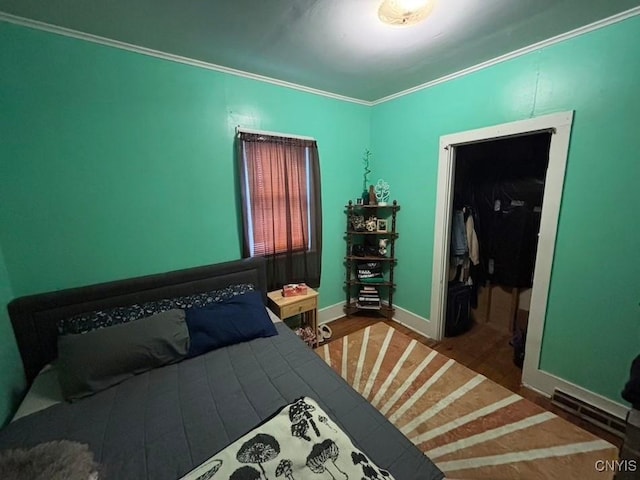 bedroom with wood finished floors, baseboards, and ornamental molding