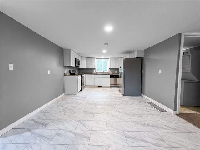 131 W Sullivanville Rd, Veteran, NY 14845 - kitchen with appliances with stainless steel finishes, stacked washer / dryer, baseboards, and light marble finish flooring