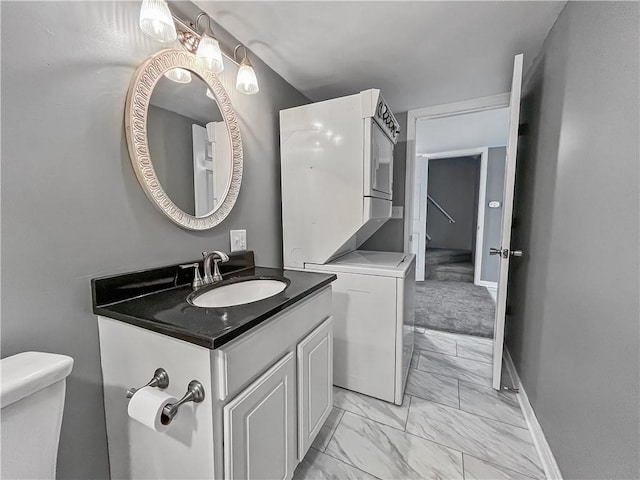 131 W Sullivanville Rd, Veteran, NY 14845 - bathroom featuring stacked washing machine and dryer, marble look tile flooring, toilet, vanity, and baseboards