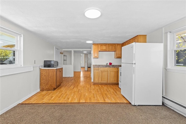 kitchen with brown cabinets, a sink, a baseboard heating unit, and white appliances