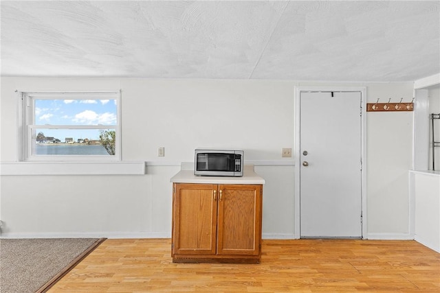 interior space with stainless steel microwave, brown cabinets, light countertops, and light wood-style floors