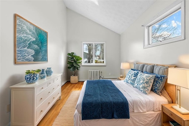 bedroom featuring lofted ceiling, radiator, light wood-style floors, and multiple windows