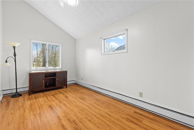 interior space featuring a baseboard heating unit, multiple windows, and light wood-type flooring