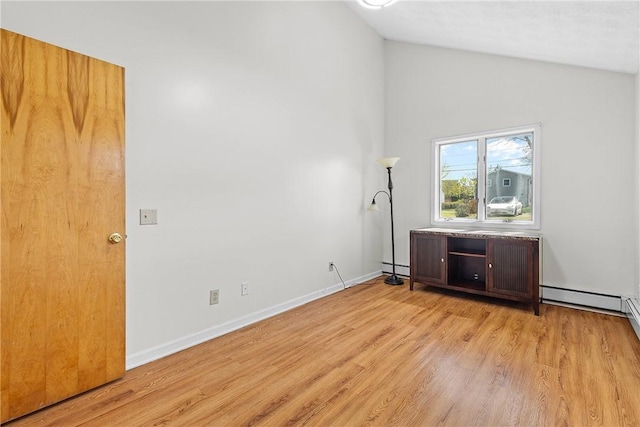 spare room featuring light wood finished floors, baseboards, a baseboard heating unit, and high vaulted ceiling