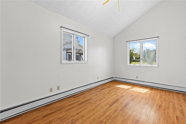 empty room featuring a baseboard heating unit, lofted ceiling, a healthy amount of sunlight, and wood finished floors