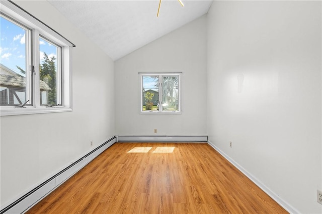 spare room featuring vaulted ceiling, baseboards, light wood-type flooring, and baseboard heating