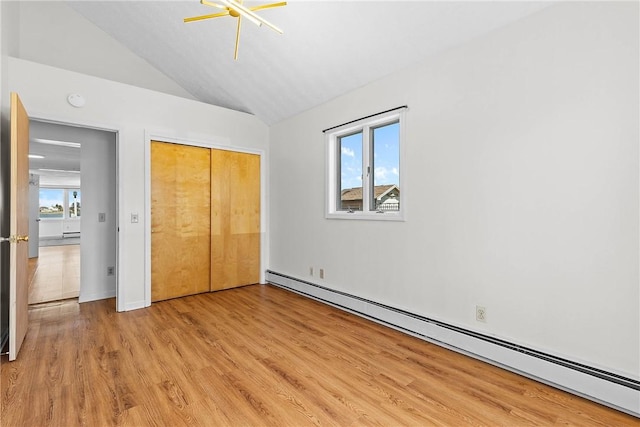 unfurnished bedroom with light wood-style flooring, a ceiling fan, a closet, lofted ceiling, and a baseboard radiator