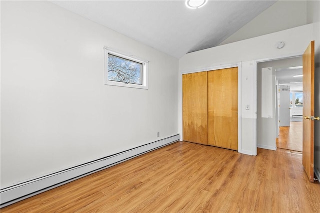 unfurnished bedroom featuring multiple windows, light wood-style flooring, a baseboard radiator, and lofted ceiling