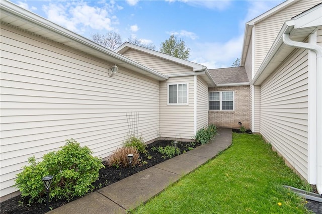 exterior space with a yard, brick siding, and a shingled roof