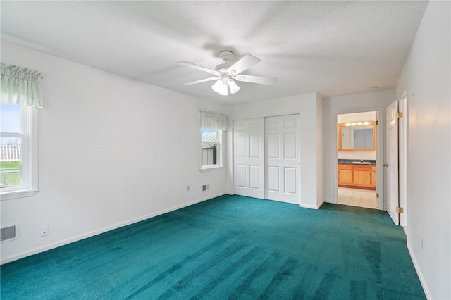 unfurnished bedroom featuring multiple windows, dark colored carpet, and visible vents
