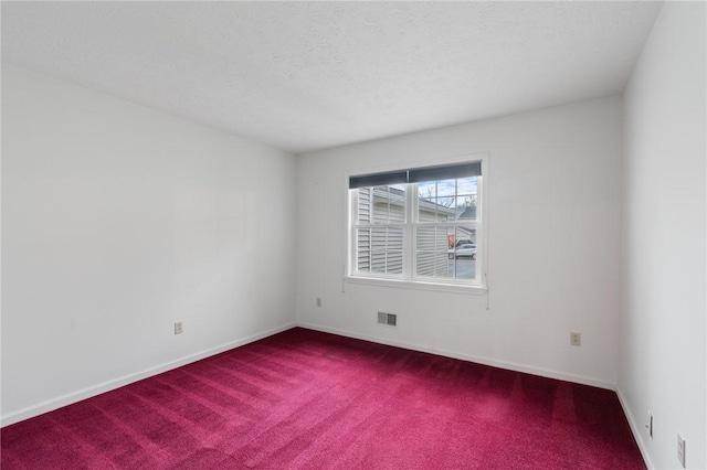spare room featuring visible vents, baseboards, and dark carpet