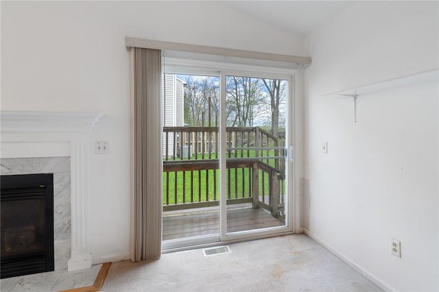 entryway featuring carpet flooring, visible vents, baseboards, vaulted ceiling, and a high end fireplace