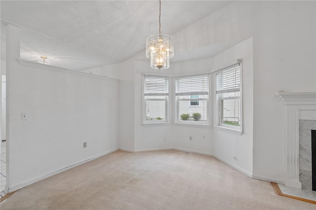 unfurnished living room featuring a premium fireplace, a chandelier, carpet, and baseboards