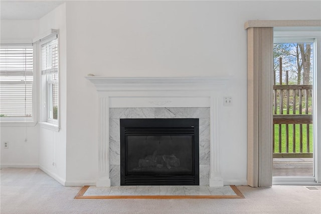 room details with baseboards, a high end fireplace, visible vents, and carpet floors