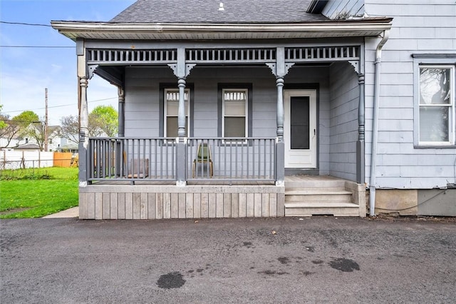 property entrance with covered porch and a shingled roof